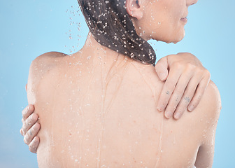 Image showing Back, woman and shower for skincare, clean and hygiene against blue studio background. Young female, girl and liquid drops for washing, body care or natural beauty for wellness, water splash or relax