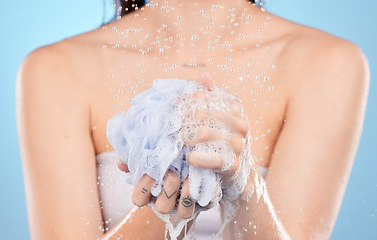 Image showing Woman, shower and hands with sponge close up or body cleaning or washing for skincare hygiene in studio. Model, luxury grooming and foam loofah for cosmetics scrub or body care in blue background