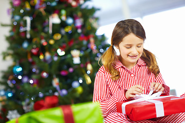 Image showing Girl opening gift box for Christmas at family home, excited and happy with holiday spirit and celebration with present. Young child with gift, happiness and festive mood, tradition and celebrate.