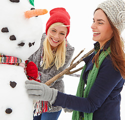 Image showing Girl friends, snowman and winter fun activity of women on a Christmas holiday, travel and vacation. Happiness, laughing and smile of a woman feeling excited in cold snow happy with funny experience