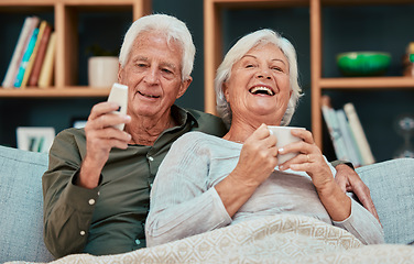 Image showing Elderly couple, laugh and relax watching tv with coffee on the living room sofa together at home. Happy senior man and woman relaxing, streaming and laughing for entertainment, movie or show on couch