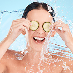 Image showing Water, beauty and cucumber with a woman in the shower in studio on a blue background for hygiene or hydration. Health, wellness and luxury with an attractive young female in the bathroom for skincare