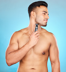 Image showing Studio, hair removal or model shaving beard or grooming his face for beauty or facial skincare wellness. Relaxing, blue background or healthy man cleaning his face with electric blade machine