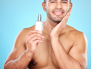 Image showing Cologne, grooming and face of a man for skincare, beauty wellness and luxury cosmetics against a blue background in studio. Self care, smile and portrait of a model with facial perfume product