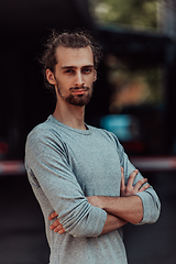 Image showing Portrait of a young successful businessman with crossed arms in front of the company