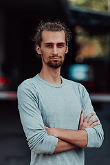 Image showing Portrait of a young successful businessman with crossed arms in front of the company