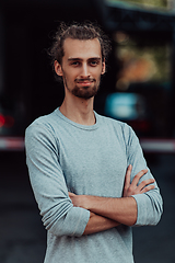 Image showing Portrait of a young successful businessman with crossed arms in front of the company