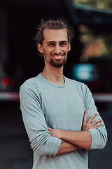 Image showing Portrait of a young successful businessman with crossed arms in front of the company