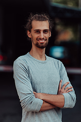 Image showing Portrait of a young successful businessman with crossed arms in front of the company