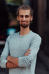 Image showing Portrait of a young successful businessman with crossed arms in front of the company