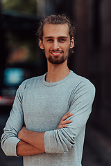 Image showing Portrait of a young successful businessman with crossed arms in front of the company