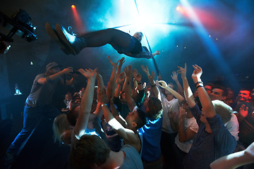 Image showing Music artist, stage dive and concert for party, nightclub or dance festival in the crowd or audience indoors. DJ, music concert and crowds of people ready to catch performer in celebration for event