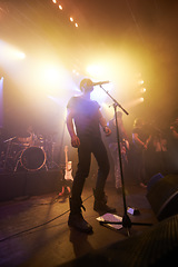 Image showing Music, rock and stage with man and microphone singing for concert, festival and party event. Light, celebration and performance with singer and band at nightclub for disco, techno or new year show