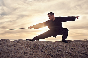 Image showing Martial arts, sword and tai chi, meditation and training at beach, sunset and outdoor in summer in Australia. Man, mindfulness and calm with balance alone in nature, ocean and meditate fo wellness