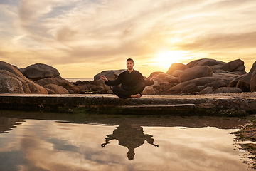 Image showing Sunset, yoga or zen man in meditation by a calm or peaceful lake or beach for a spiritual mindfulness exercise. Nature, wellness or healthy yogi in a lotus pose training his relaxed body to meditate