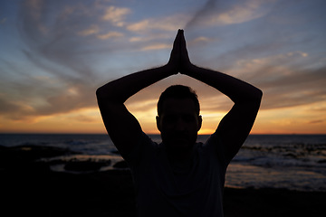 Image showing Sunset, yoga and beach fitness with a flexible man working out for exercise and strength. Ocean, silhouette and male yogi stetching for spiritual and chakra enlightenment while meditating outside