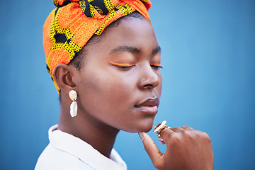 Image showing Cosmetics, skincare and black woman with head wrap, natural beauty and wellness against a blue studio background. Jamaican female, girl and makeup for eyelash color, traditional headscarf and mockup.