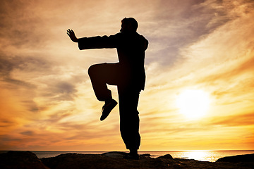 Image showing Beach, silhouette and karate man at sunset in Canada for peace, focus and training for competition. Balance, exercise and fitness of professional martial arts athlete at ocean with dusk sun.