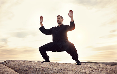 Image showing Karate, martial arts and man training by ocean for mindfulness, body wellness and balance in nature. Sports, fitness and male athlete doing exercise, workout and stretching for taekwondo by sea