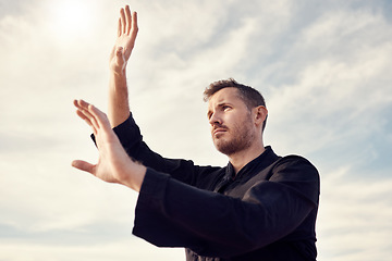 Image showing Karate man, fitness and exercise against a cloudy sky with lens flare for spiritual workout, martial arts and training outdoor. Athlete male ready to fight tai chi, chi gong or taekwondo with hands