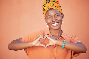 Image showing Black woman, hands or heart sign on wall background with fashion, trendy or stylish clothes for love, support or trust. Portrait, smile or happy student and hand gesture, hope emoji or orange mockup