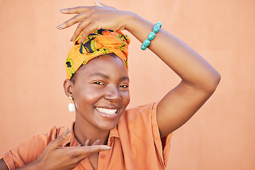 Image showing Face portrait, fashion and black woman with turban in studio on an orange background. Beauty pose, hands frame and makeup of happy female model from Nigeria in stylish traditional African head scarf.