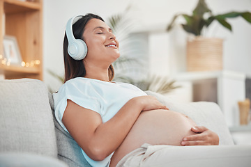 Image showing Music, headphones and pregnant woman relax on sofa in home living room streaming radio or podcast. Pregnancy, meditation and female from Canada on couch listening to song, audio or sound in house.