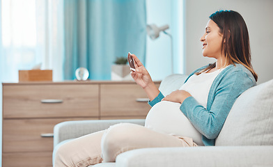Image showing Pregnant, ultrasound and baby with a mother in the living room, sitting on a sofa in her home alone. Happy, smile and pregnancy with a woman looking a photograph of her infant in the house lounge