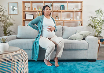 Image showing Pregnant woman, discomfort and back pain sitting on the living room sofa and holding tummy at home. Female going through pregnancy contractions, pain or medical health issues and back ache on couch