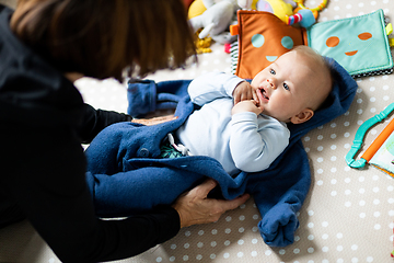 Image showing Happy family moments. Grandmother dressing up her grandson baby boy while he is laying on children's playing mat Positive human emotions, feelings, joy...