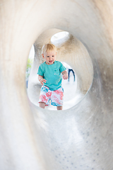 Image showing Child playing on outdoor playground. Toddler plays on school or kindergarten yard. Active kid on stone sculpured slide. Healthy summer activity for children. Little boy climbing outdoors.