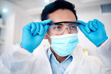 Image showing Covid, science and goggles with a man at work on research or innovation in a laboratory as a scientist. Doctor, futuristic and face with a male working in development of a corona virus treatment