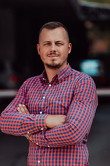 Image showing A successful young businessman in a shirt, with crossed arms, poses outdoors, confident expression on his face.