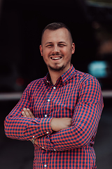 Image showing A successful young businessman in a shirt, with crossed arms, poses outdoors, confident expression on his face.