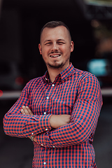 Image showing A successful young businessman in a shirt, with crossed arms, poses outdoors, confident expression on his face.