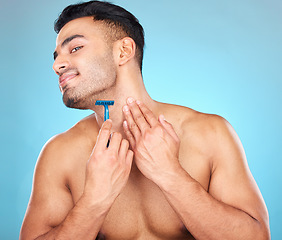 Image showing Shaving, grooming and man with a razor for a beard, skincare and hygiene against a blue background in studio. Cosmetic, health and model with a smile to shave hair from face for clean facial beauty