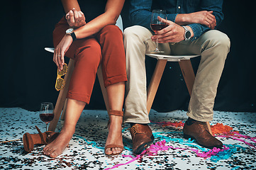 Image showing Feet, man and woman sitting at a party to celebrate new years eve and socialise together. Legs, couple and celebrating while partying together at a festive celebration or event with confetti