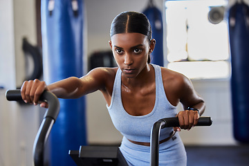 Image showing Cycling, gym bicycle and woman focus on fitness performance, air bike workout or cardio training for strong body health. Wellness motivation, machine and serious girl working on exercise challenge