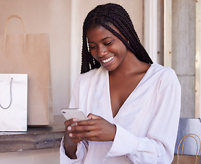 Image showing Black woman, smartphone and shopping, happy and communication, retail and sale with bargain, discount with technology. Phone, shopping bag in mall and social media, text message and mobile app.