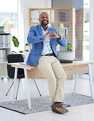 Image showing African businessman, heart sign or office for smile, happiness or sitting on desk with love. Black man, corporate executive or finance job with hands signal, care or solidarity for support in Atlanta