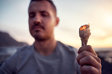 Image showing Man, hand and burning sage on the beach while meditating for spiritual peace and zen mindfulness. Herb, burn and alternative cleanse ceremony to meditate for smudge during a seaside peaceful time
