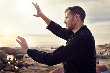 Image showing Tai chi, fitness and martial arts with man at beach for exercise and karate, self defense and zen with peace outdoor profile. Workout on rocks, energy balance and nature, wellness and calm sunrise.