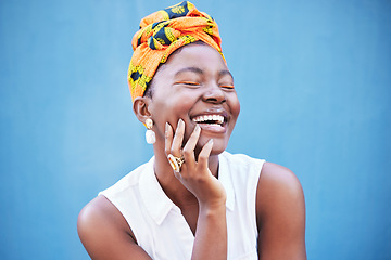 Image showing Happy black woman, african fashion and culture with turban scarf on blue wall background in Nigeria. Happiness, beauty and cultural style of young black person laughing with jewelry, makeup and smile