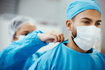 Image showing Surgeon, doctor or medical man with nurse helping with clean scrubs and face mask for surgery, healthcare and safety in theatre. Emergency, ppe and operation staff in a hospital for life insurance