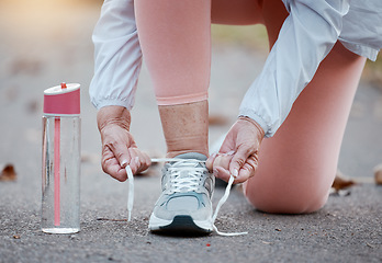 Image showing Senior woman fitness, exercise and shoes with hands tying laces while running on a concrete road or street. Workout, training and cardio with a elderly female hand getting ready for a run routine