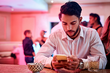 Image showing Phone, party and waiting with a man in a nightclub, checking his text message alone while his date is late. Contact, stood up and contact with a male in a club, browsing social media on new year