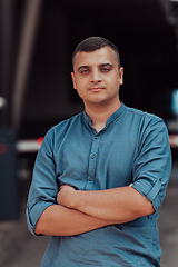 Image showing A successful young businessman in a shirt, with crossed arms, poses outdoors, confident expression on his face.