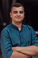 Image showing A successful young businessman in a shirt, with crossed arms, poses outdoors, confident expression on his face.