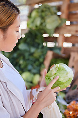 Image showing Grocery store, lettuce and Asian woman shopping and looking at vegetable quality and sale. Customer holding and checking vegetables price on salad promotion in a health food shop or supermarket