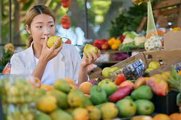 Image showing Grocery shopping, Asian woman and fruit choice at outdoor market. Food, fruits and female smelling and choosing healthy, delicious and fresh pears for health, wellness and vitamin c at store or shop.